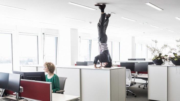 Businessman doing headstand on filing cabinet
