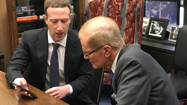 Facebook CEO Mark Zuckerberg holds a mobile phone while speaking with Senator Bill Nelson in Washington