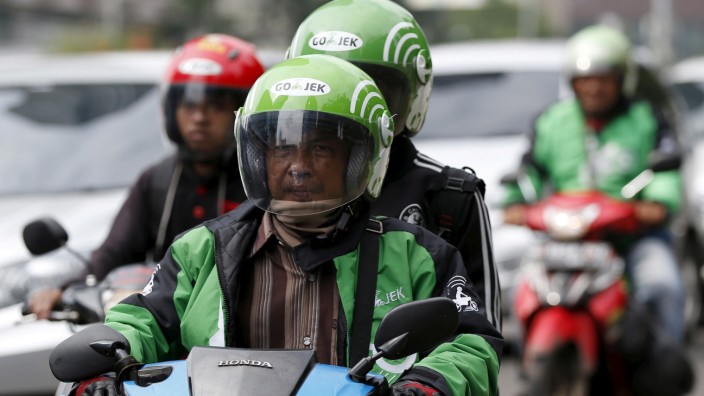FILE PHOTO: Driver and passenger ride on a motorbike, part of the Go-Jek ride-hailing service, on a busy street in central Jakarta