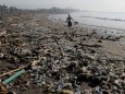 A local resident walks along a section of Matahari Terbit beach covered in plastic and other debris washed ashore by seasonal winds near Sanur, Bali