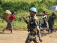 An Indian soldier, serving in MONUSCO, patrols past Congolese women walking to the market centre in Masisi