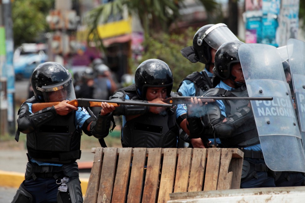 Riot policemen fire rubber bullets toward university students protesting over a controversial reform to the pension plans of the Nicaraguan Social Security Institute in Managua