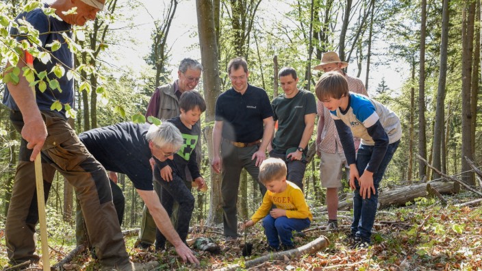 Dietramszell: Waldumbau mit kleinen Händen: Revierförster Robert Nörr (links, mit schwarzem Hemd) hilft den Kindern beim Einsetzen der Bäume.