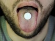 Bearded man swallows a pill. Close up of man showing tablet on the tongue and swallows it, the concept of medicine and health; SZ-Magazin
