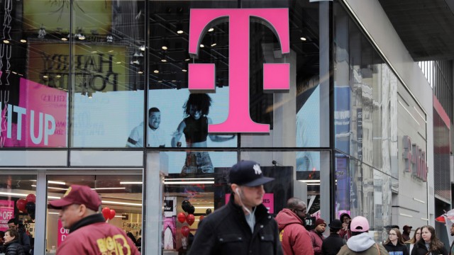 Pedestrians walk past a T-Mobile store in New York