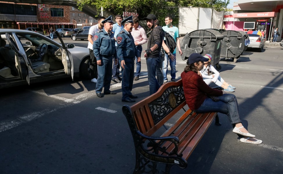 Armenian opposition supporters sit on a bench as they block a road, after protest movement leader Nikol Pashinyan announced a nationwide campaign of civil disobedience in Yerevan