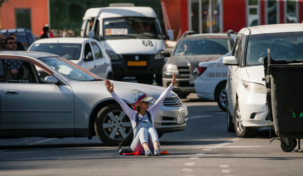 An Armenian opposition supporter sits on the ground as she blocks a road, after protest movement leader Nikol Pashinyan announced a nationwide campaign of civil disobedience in Yerevan