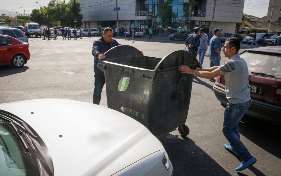 Armenian opposition supporters move a garbage bin to block a road, after protest movement leader Nikol Pashinyan announced a nationwide campaign of civil disobedience in Yerevan