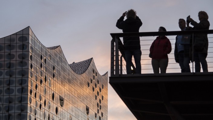 Touristen fotografieren während des Sonnenuntergangs die Elbphilharmonie in Hamburg.
