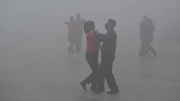 FILE PHOTO: People wearing masks dance amid heavy smog during a polluted day at a square in Fuyang