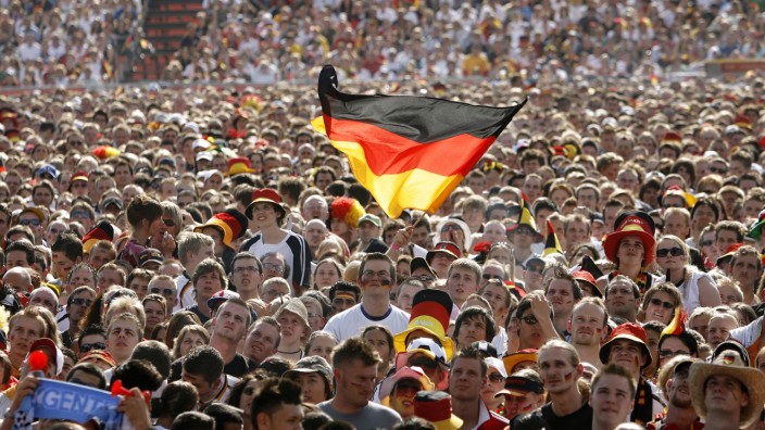 A soccer fan waves a German flag during a public screening of the World Cup soccer match between Germany and Argentina in Hamburg