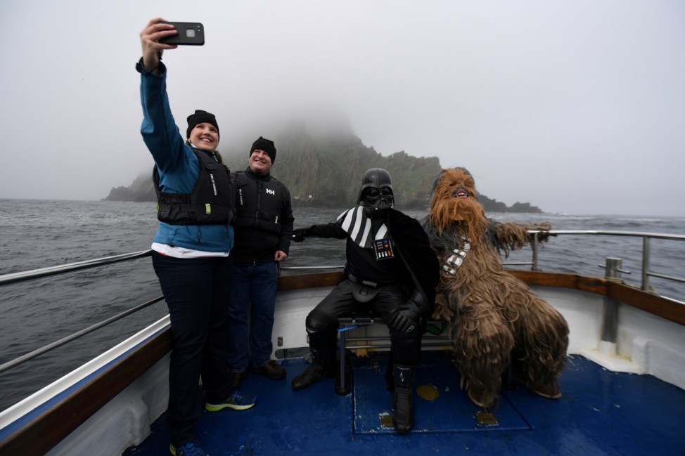 Holidaymakers take a selfie, along with Star Wars fans dressed in costume as Darth Vader and Chewbacca, on a boat trip to Skellig Island during the inaugural 'May The 4th Be With You' festival in the County Kerry village of Portmagee