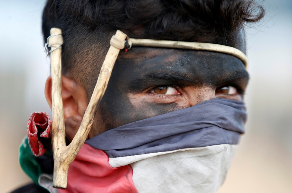 Palestinian demonstrator with a slingshot looks on during a protest against U.S. embassy move to Jerusalem and ahead of the 70th anniversary of Nakba, at the Israel-Gaza border, east of Gaza City