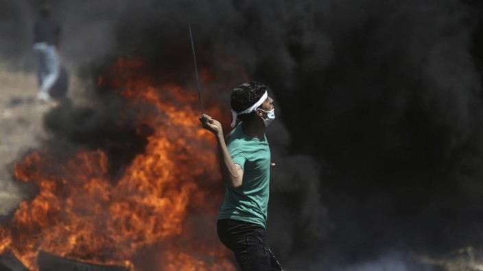 Proteste in Palästinensergebieten: Ein palästinensischer Demonstrant im Gaza-Streifen wirft einen Stein in Richtung israelischer Soldaten.