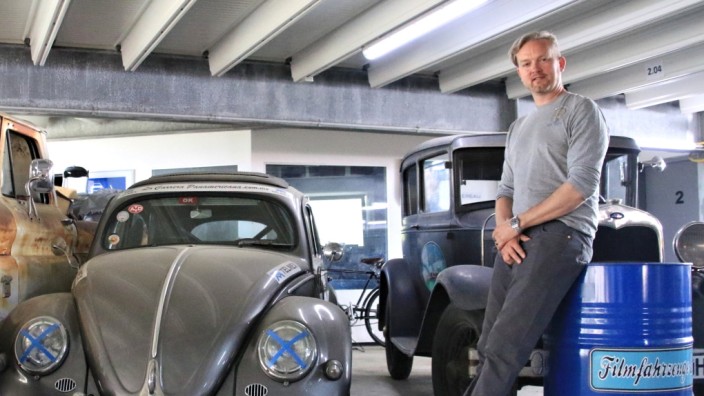Filmautos in Berlin: Sven Liedtke von der Verleihfirma Moviecars neben einem VW Käfer und einem rostigen Pick-up von Chevrolet.