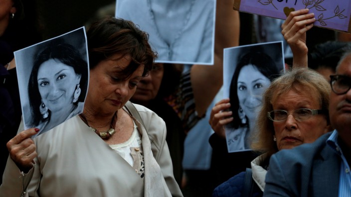 People hold up posters and pictures of assassinated anti-corruption journalist Daphne Caruana Galizia during a vigil and demonstration marking seven months since her murder in a car bomb, at her makeshift memorial outside the Courts of Justice in Valletta