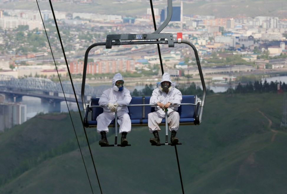 Employees of the Derate pest control company use a ski lift as they move uphill to spray pesticide to kill ticks carrying encephalitis at the Bobrovy Log resort area in Taiga district outside Krasnoyarsk