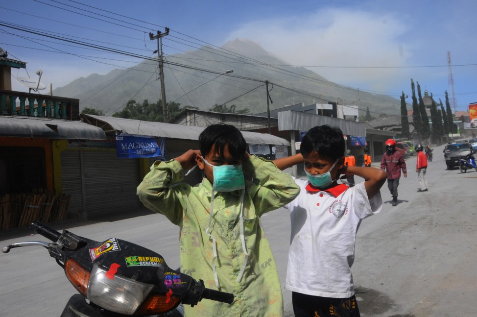 Children put on masks handed out by volunteers after Mount Merapi volcano erupted in Boyolali