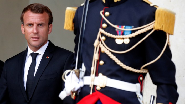 French President Emmanuel Macron stands next to a Republican Guard outside the Elysee Palace in Paris