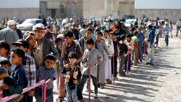 People queue outside a charity food distribution center to get the iftar meal during the holy month of Ramadan in Sanaa