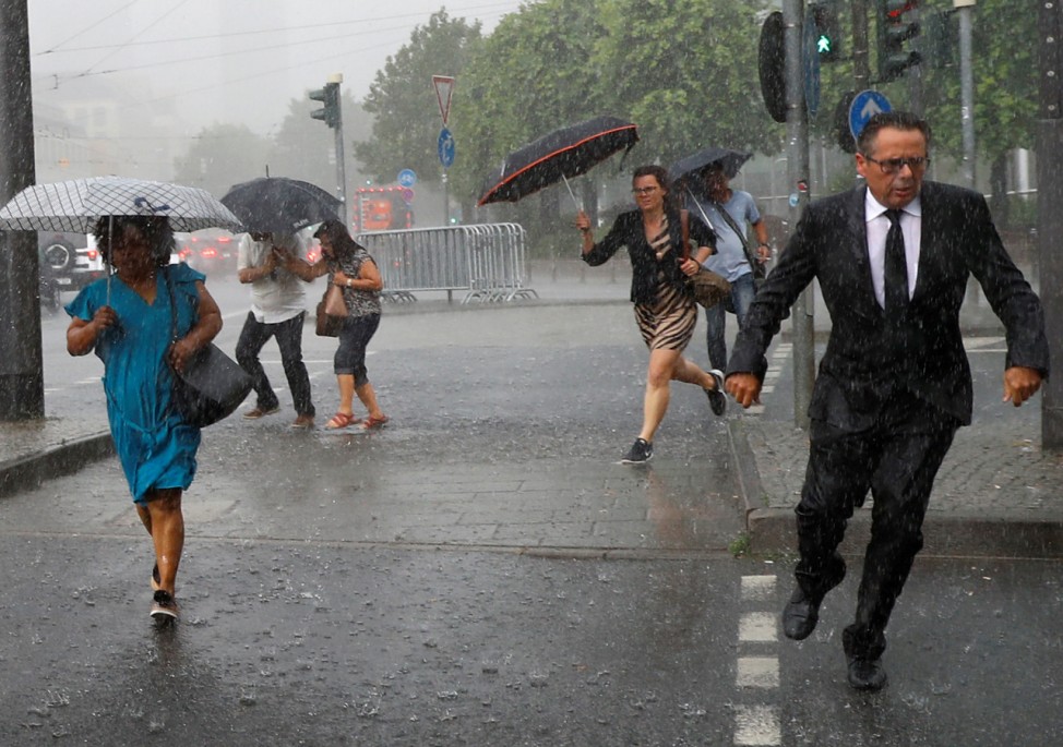People cross a street during heavy rain in Frankfurt