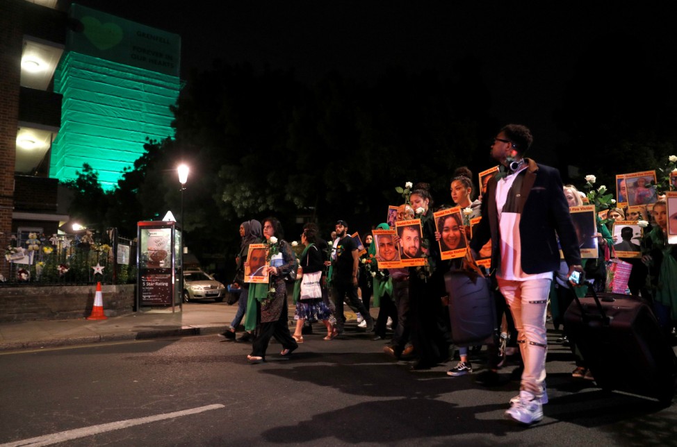 Relatives, survivors and friends of victims of the Grenfell tower fire walk to the tower to hold a vigil, one year after the fire in London