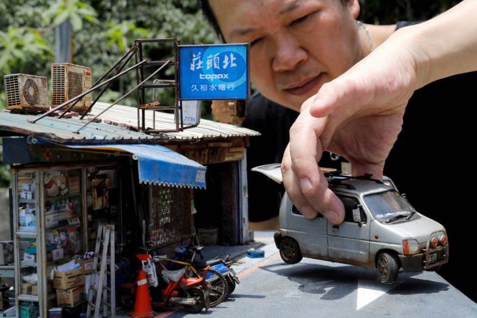 Taiwanese artist Hank Cheng poses with his miniature model of Taipei street scenes, in New Taipei City