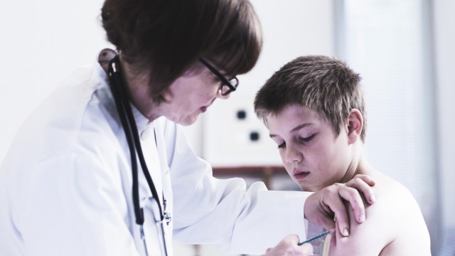 Doctor giving boy an injection in medical practice model released Symbolfoto PUBLICATIONxINxGERxSUIx