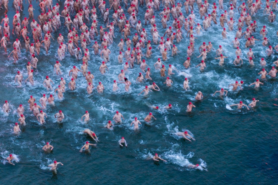 Participants of the Dark Mofo Nude Solstice Swim are seen in the River Derwent at dawn, in Hobart