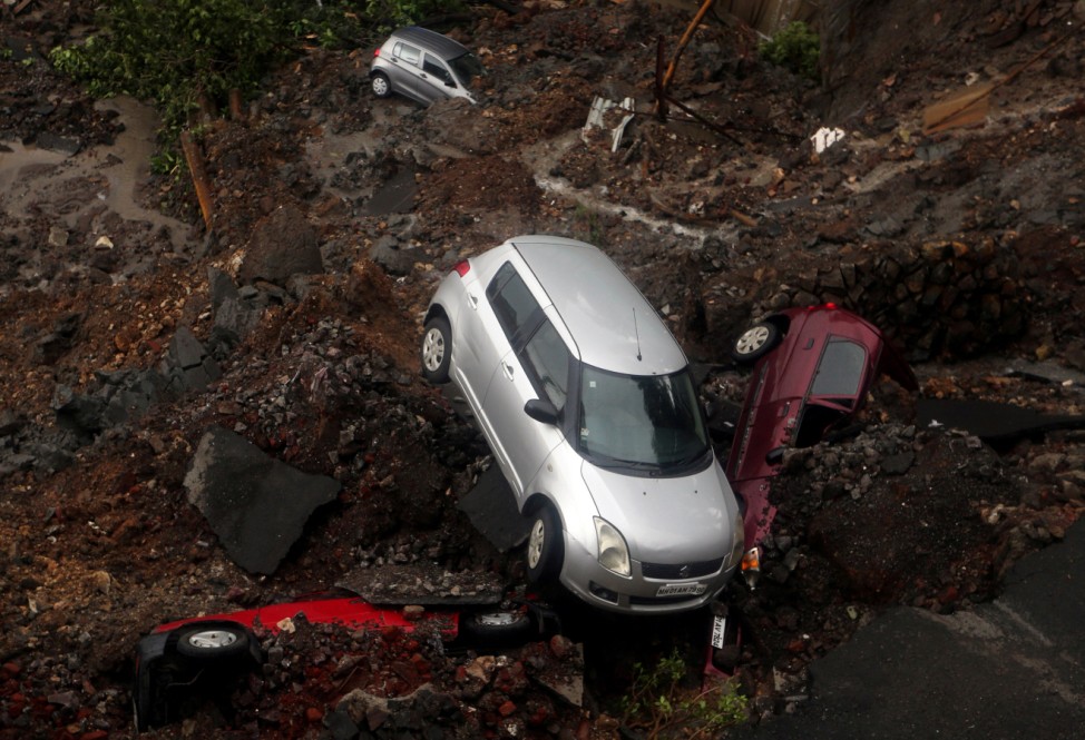 Cars are seen amidst debris after the wall of a residential building collapsed due to heavy rains in Mumbai