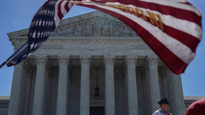 A man holds a flag outside the U.S. Supreme Court, as the Trump v. Hawaii case regarding travel restrictions in the U.S. remains pending, in Washington