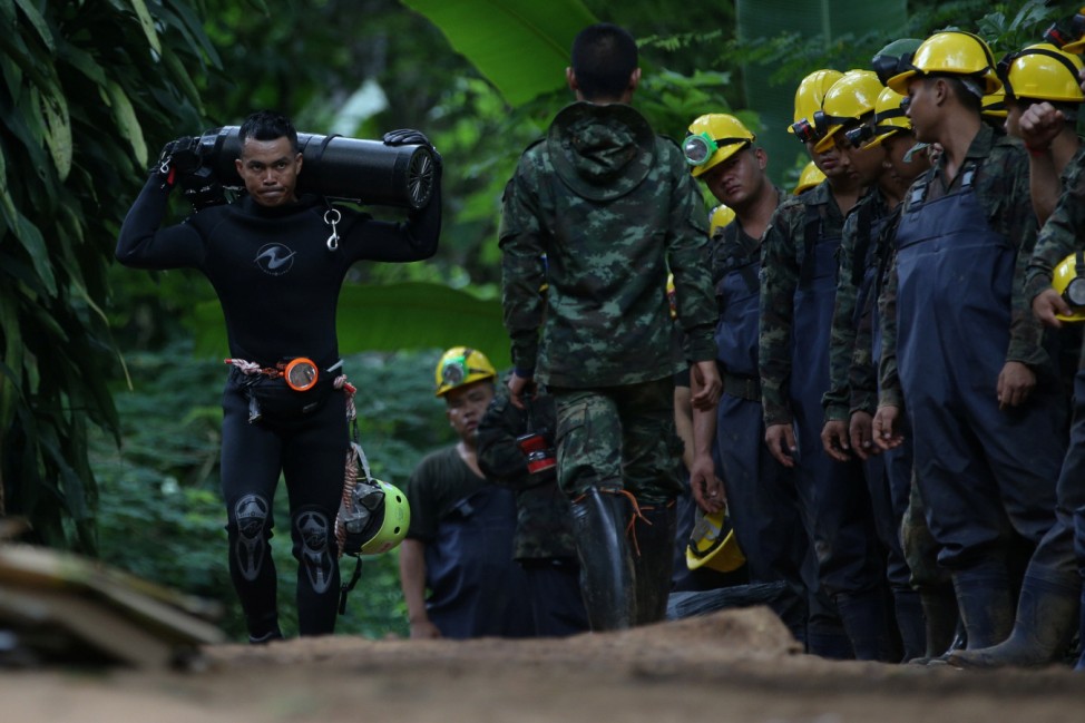 A diver carries an oxygen tank as he leaves the Tham Luang cave complex, where 12 boys and their soccer coach are trapped, in the northern province of Chiang Rai