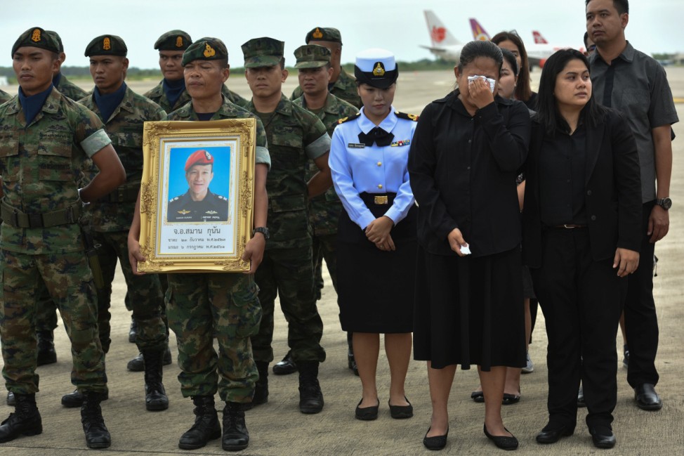 An honour guard hold up a picture of Samarn Kunan as family members weep at an airport in Rayong province