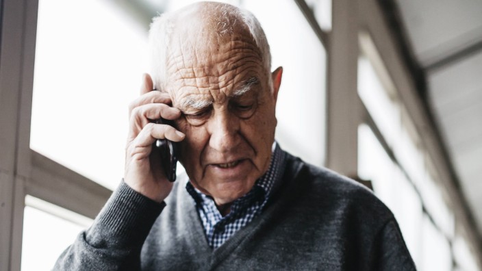 Elderly man reviewing the ceramic vase talking on the phone model released Symbolfoto property rele