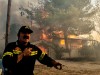 Ein Feuerwehrmann vor einem brennenden Haus bei Athen