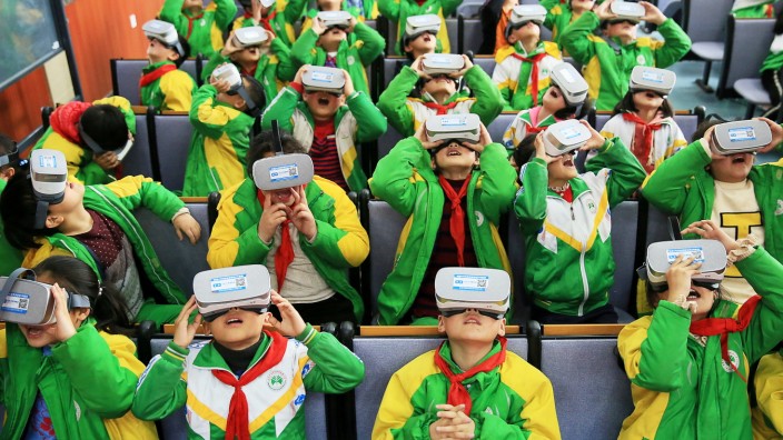 Primary school students wear virtual reality (VR) headsets inside a classroom in Xiangxi, Hunan