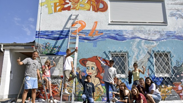 Buntes Wandbild: Stolz auf ihr Werk: Lenard Niedring (links) und zehn Buben und Mädchen aus der Mittelschule präsentieren die bemalte Fassade des Freibades in Maisach.