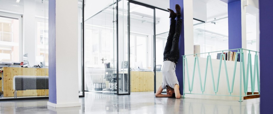 Businessman doing headstand against wall in office model released Symbolfoto property released PUBLI