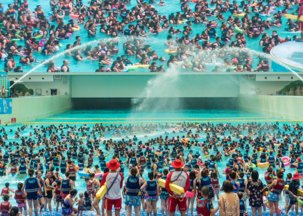 People swim under a giant screen at an indoor swimming pool on a hot day in Chengdu