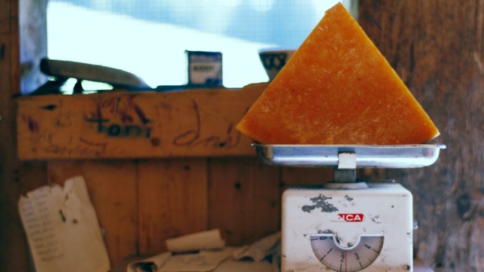 A piece of traditionally made Alp cheese is placed on scales in the cheese storage at the mountain pasture Unterbaergli above Sigriswil