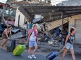 FILE PHOTO - Foreign tourists pull their suitcases as they walk past damaged buildings following a strong earthquake in Pemenang, North Lombok,