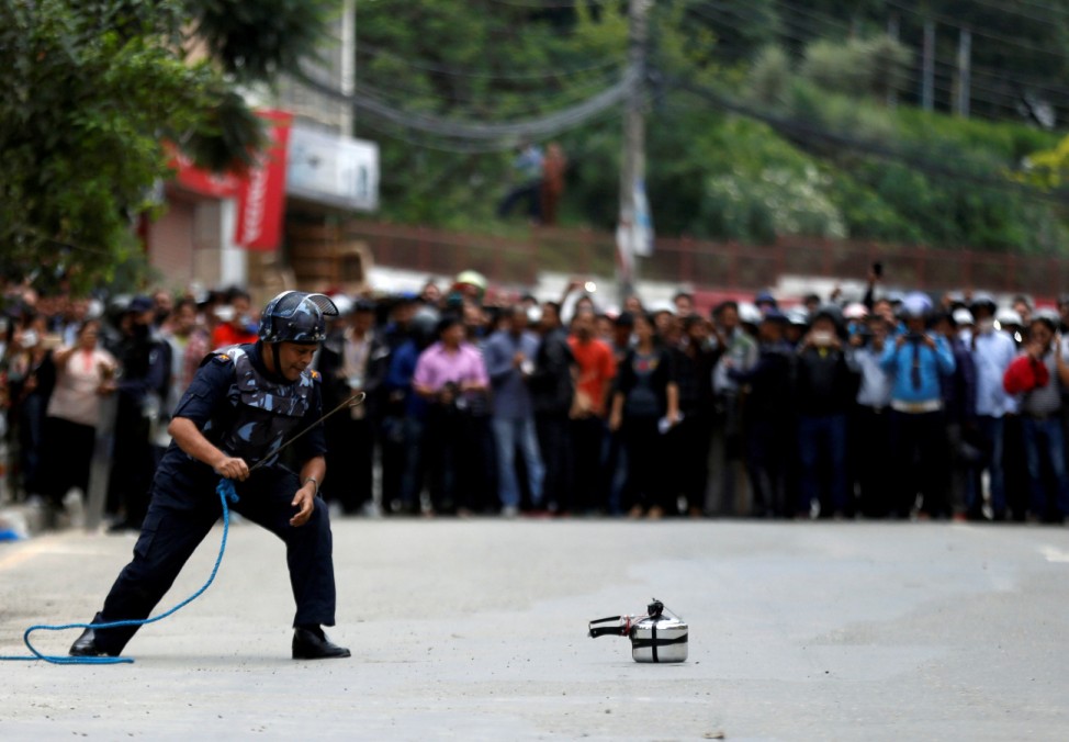 A member of Nepalese police checks a pressure cooker suspected of being an improvised bomb during a bomb scare in Lalitpur