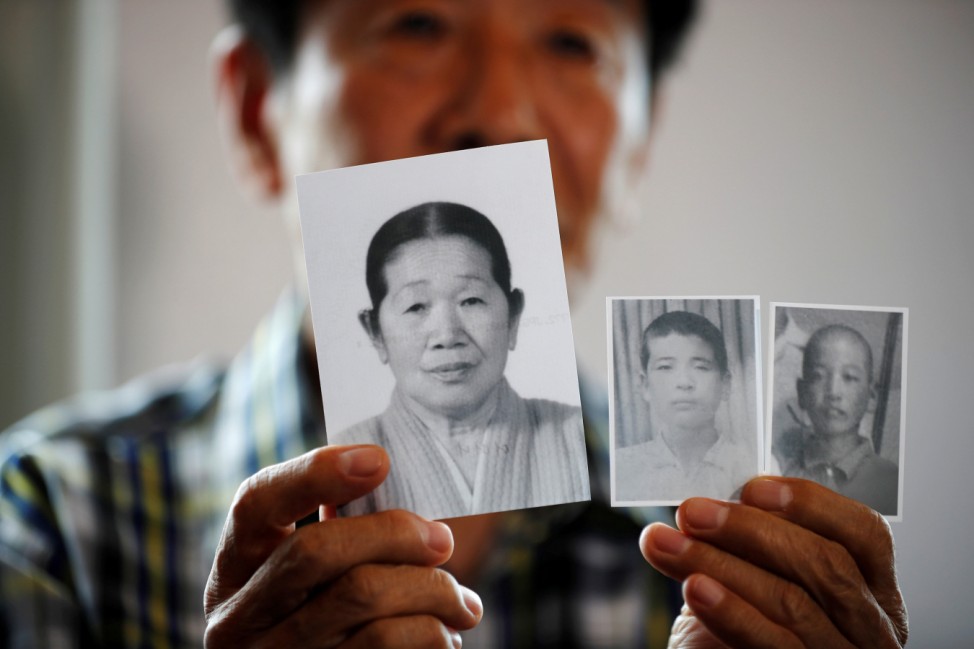 A man selected as a participant for a reunion shows pictures of his deceased mother and little brothers living in North Korea, at a hotel used as a waiting place in Sokcho