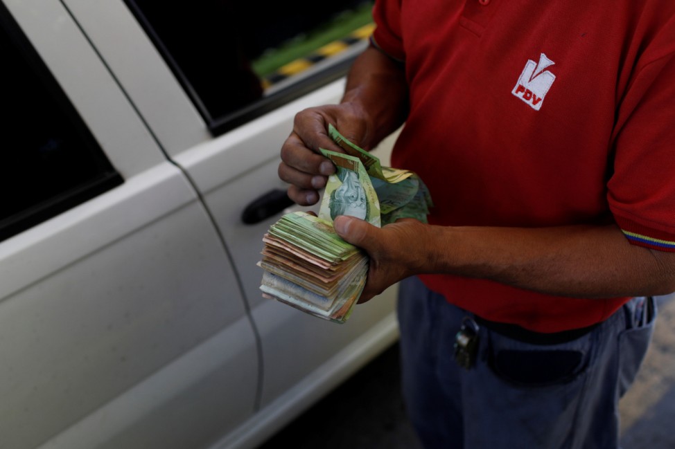 A gas station worker counts Venezuelan bolivar notes at a gas station of the Venezuelan state-owned oil company PDVSA in Caracas