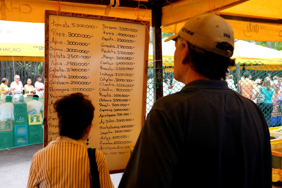 People check prices of fruits and vegetables in a street market in Caracas