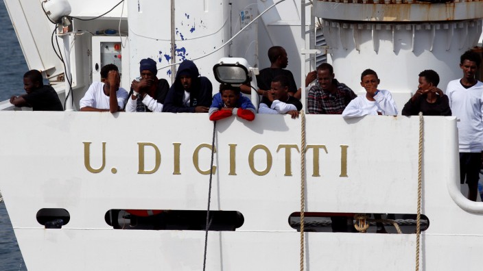 Migrants waits to disembark from Italian coast guard vessel 'Diciotti' as they arrive at the port of Catania