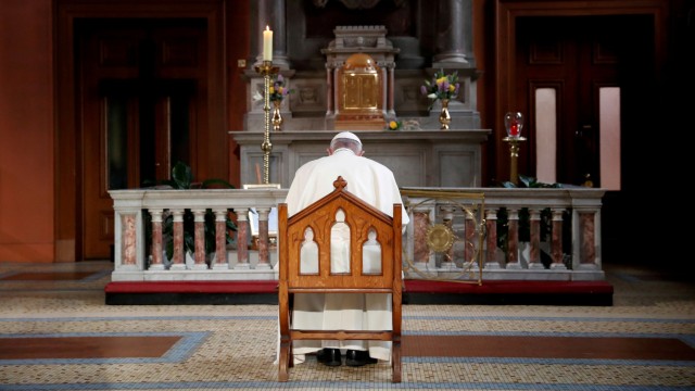 Pope Francis prays in front of a candle lit to remember victims of abuse by the church, inside St Mary's Pro Cathedral during his visit to Dublin