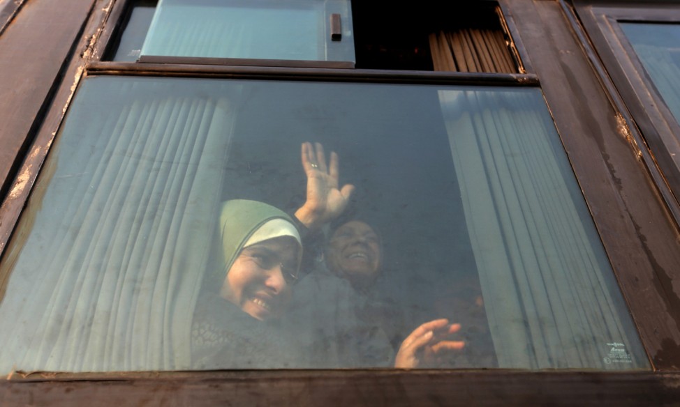 Palestinian woman waves from a bus upon her return from the annual Haj pilgrimage in Mecca, at Rafah border crossing in the southern Gaza Strip
