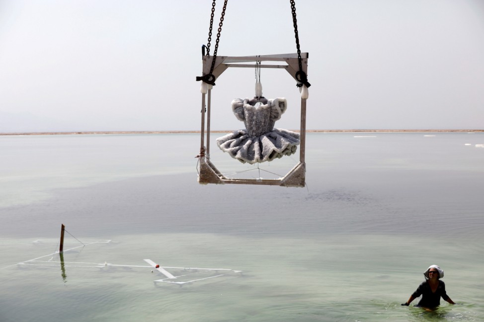 Israeli artist Sigalit Landau looks up at her artwork, a ballerina's tutu covered in salt crystal formations as it is removed from the hyper-saline waters of the southern Dead Sea, Israel