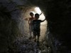 FILE PHOTO: Children walk in a makeshift shelter in an underground cave in Idlib